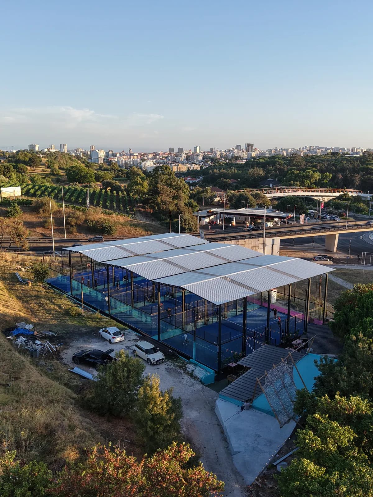 O clube em plano aproximado, com o viaduto da autoestrada e a linha do horizonte de Lisboa por trás.
